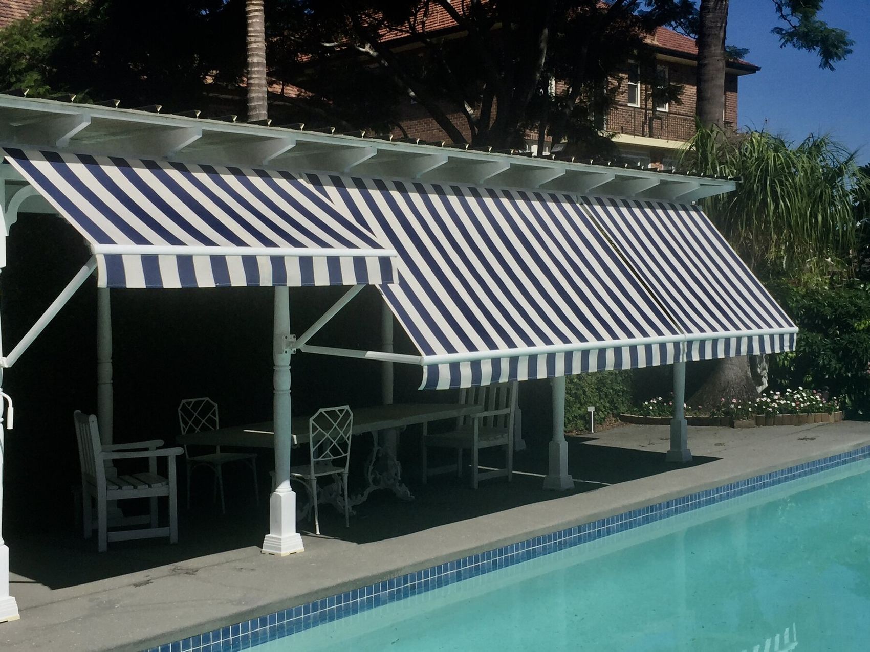 Navy and white striped awnings shading a poolside pergola