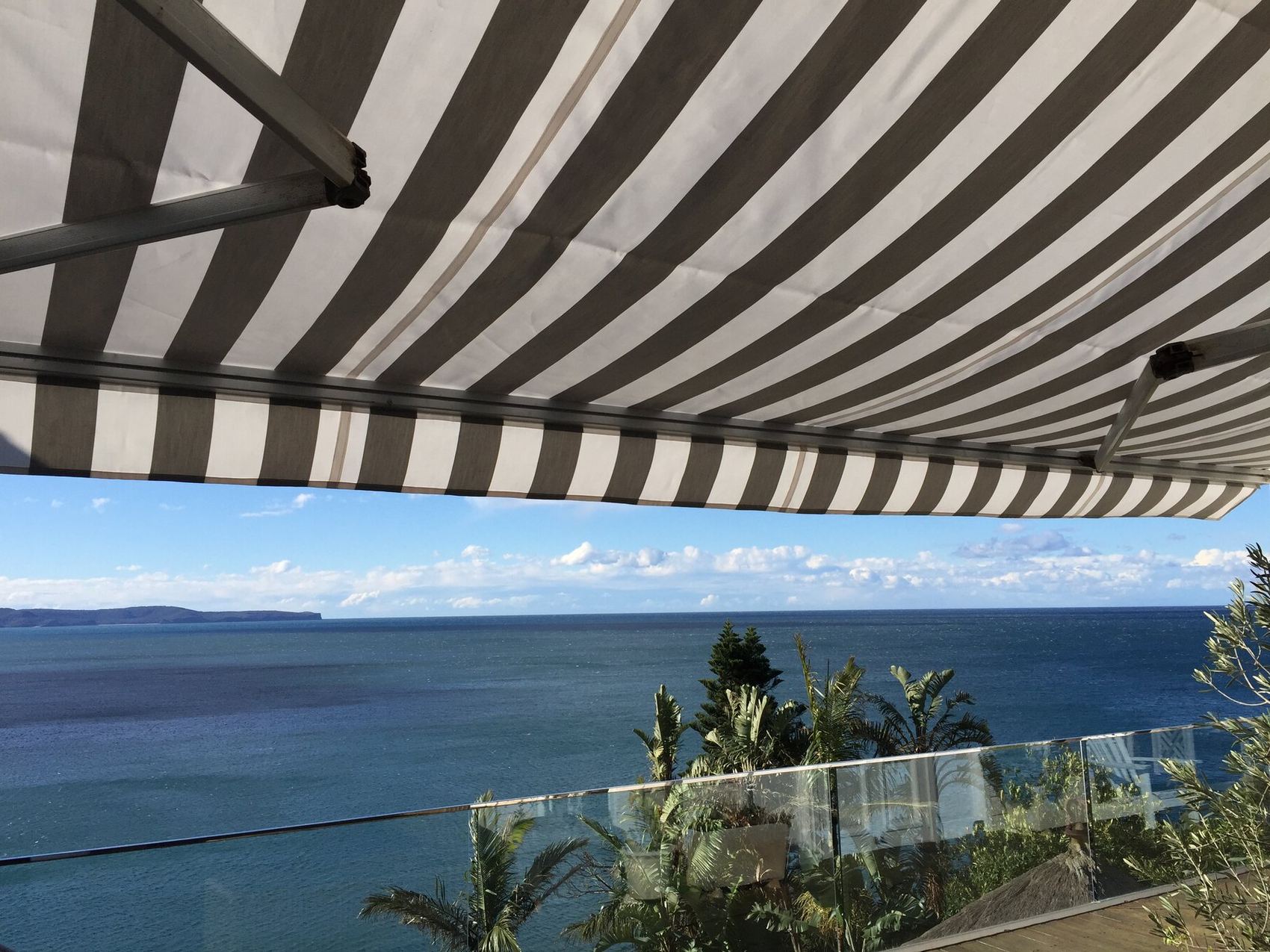 Underside of a striped folding arm awning looking out over the water