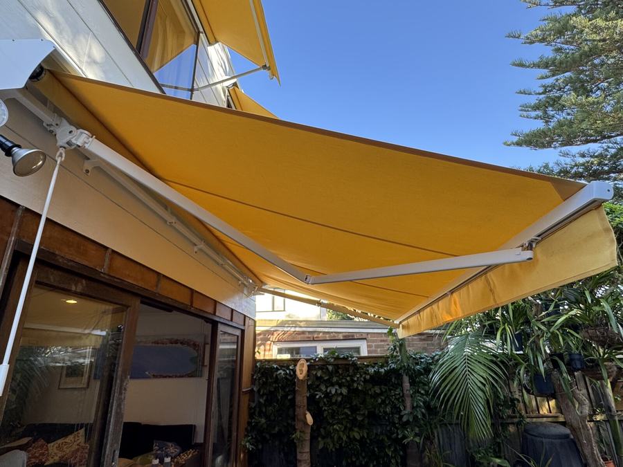 Yellow folding arm awning over a balcony